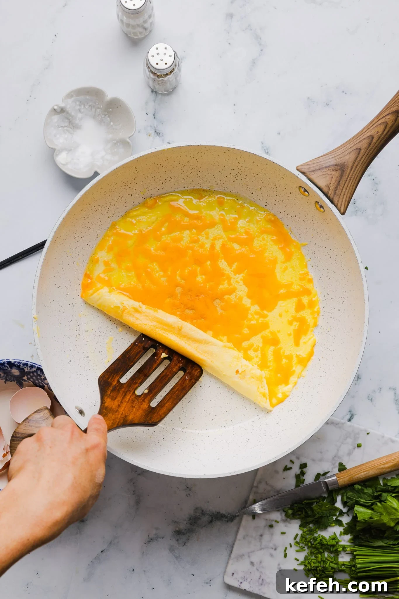 This easy cottage cheese omelette is loaded with creamy, salty cottage cheese and sharp cheddar. It's a protein powerhouse! Folding a cottage cheese omelette over a cheddar cheese filling.
