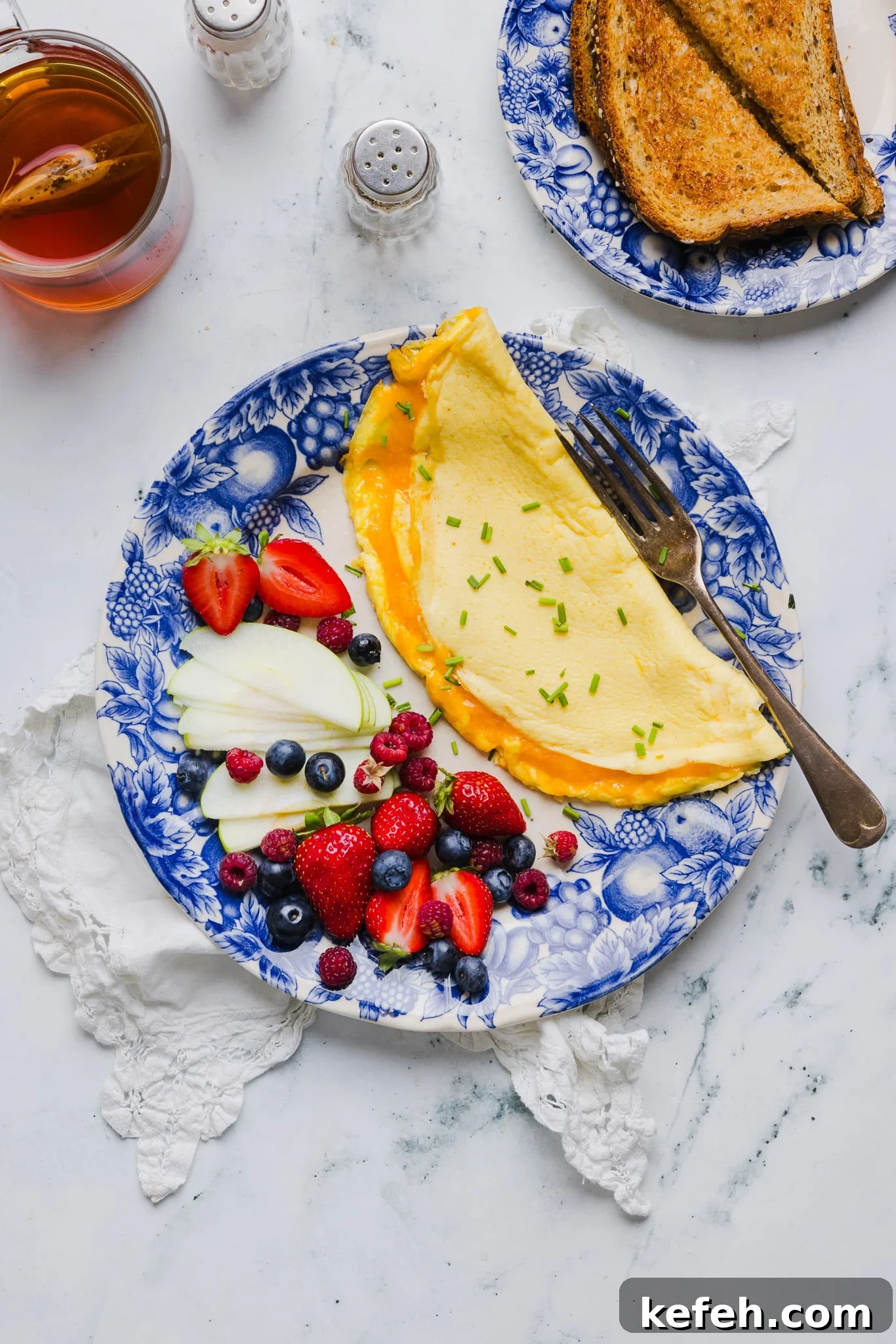 This easy cottage cheese omelette is loaded with creamy, salty cottage cheese and sharp cheddar. It's a protein powerhouse! Overhead image of a cottage cheese omelette on a plate with fresh fruit.