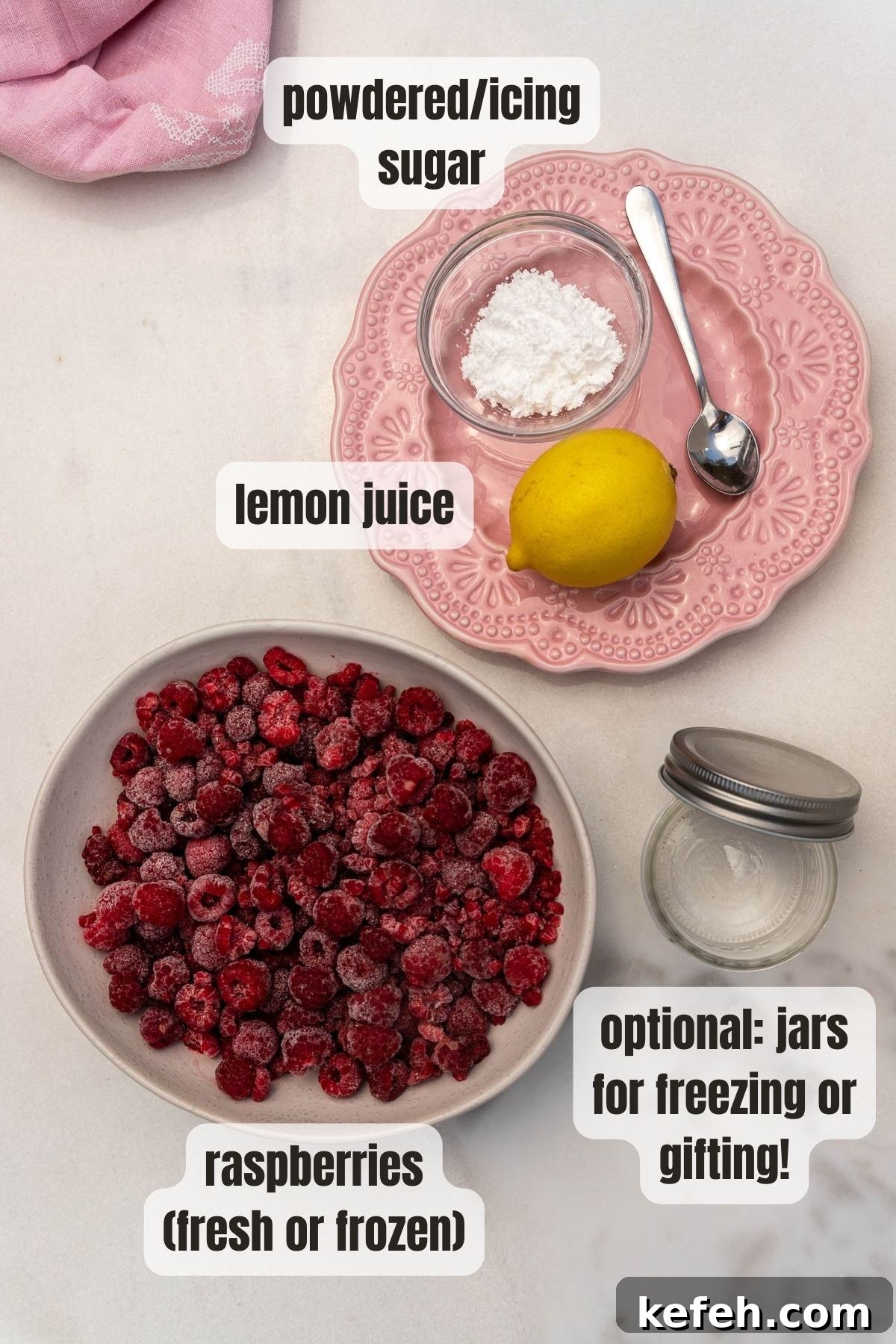 Overhead view of the 3 ingredients for homemade raspberry puree including a bowl of frozen raspberries, a lemon, powdered sugar and an empty jar for possible freezing or gifting.
