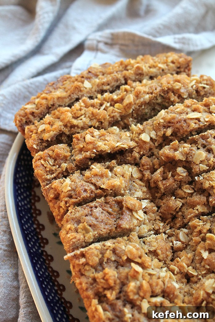 A sliced loaf of zucchini bread with brown sugar streusel on an oval platter.