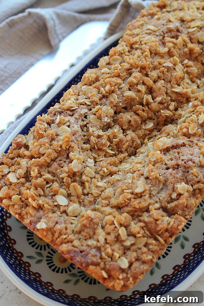 A whole loaf of zucchini bread with brown sugar streusel on an oval Polish pottery plate.
