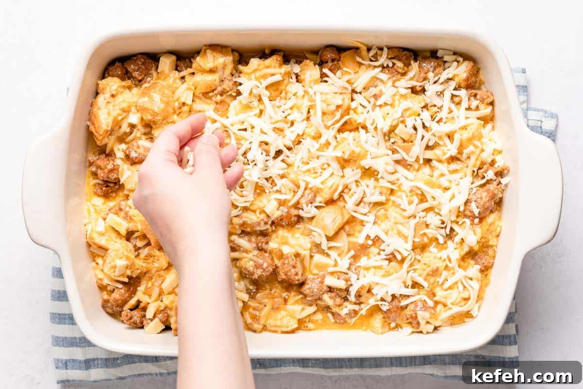 hand sprinkling shredded cheese overtop uncooked casserole
