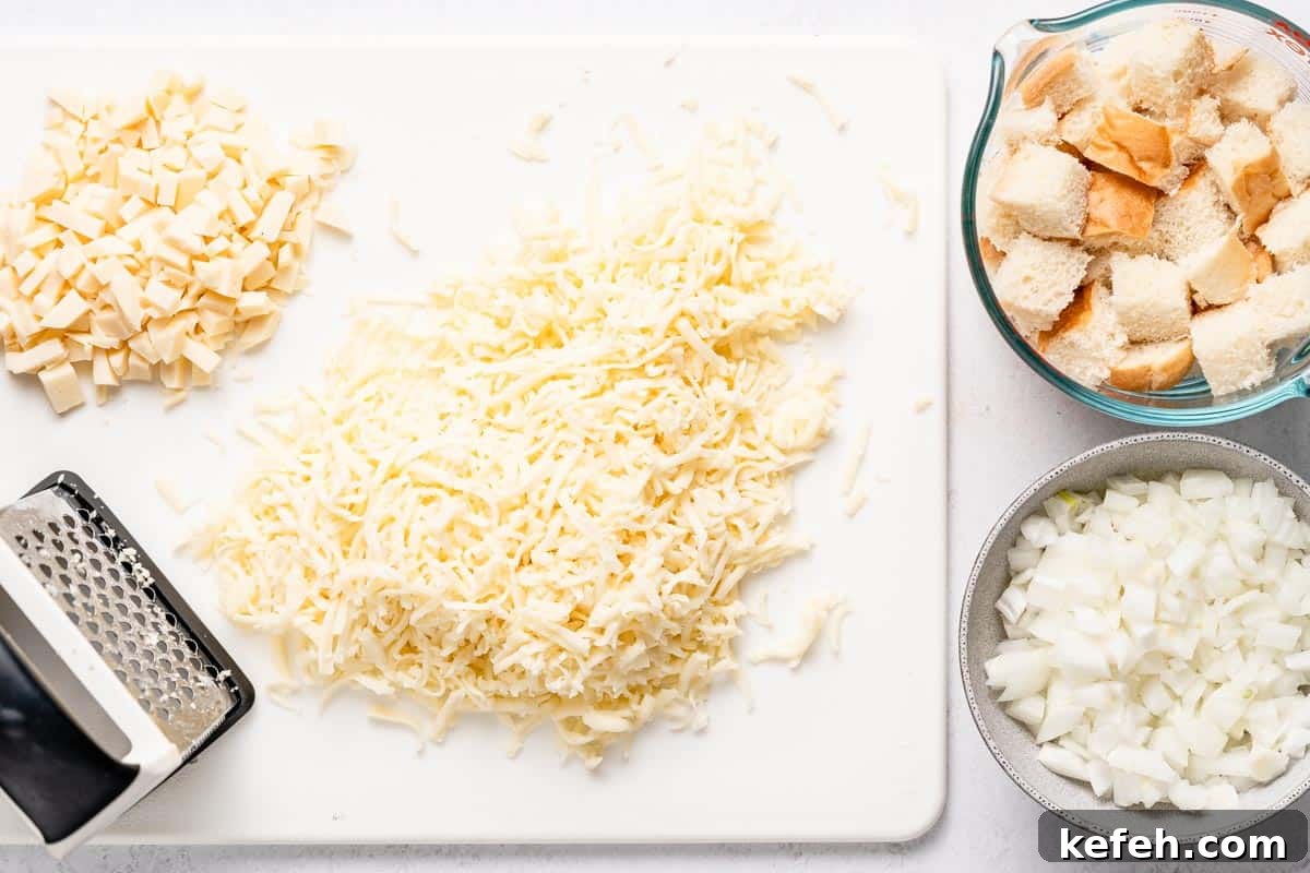 shredded cheese on cutting board and with bowls of bread cubes and chopped onion on the side