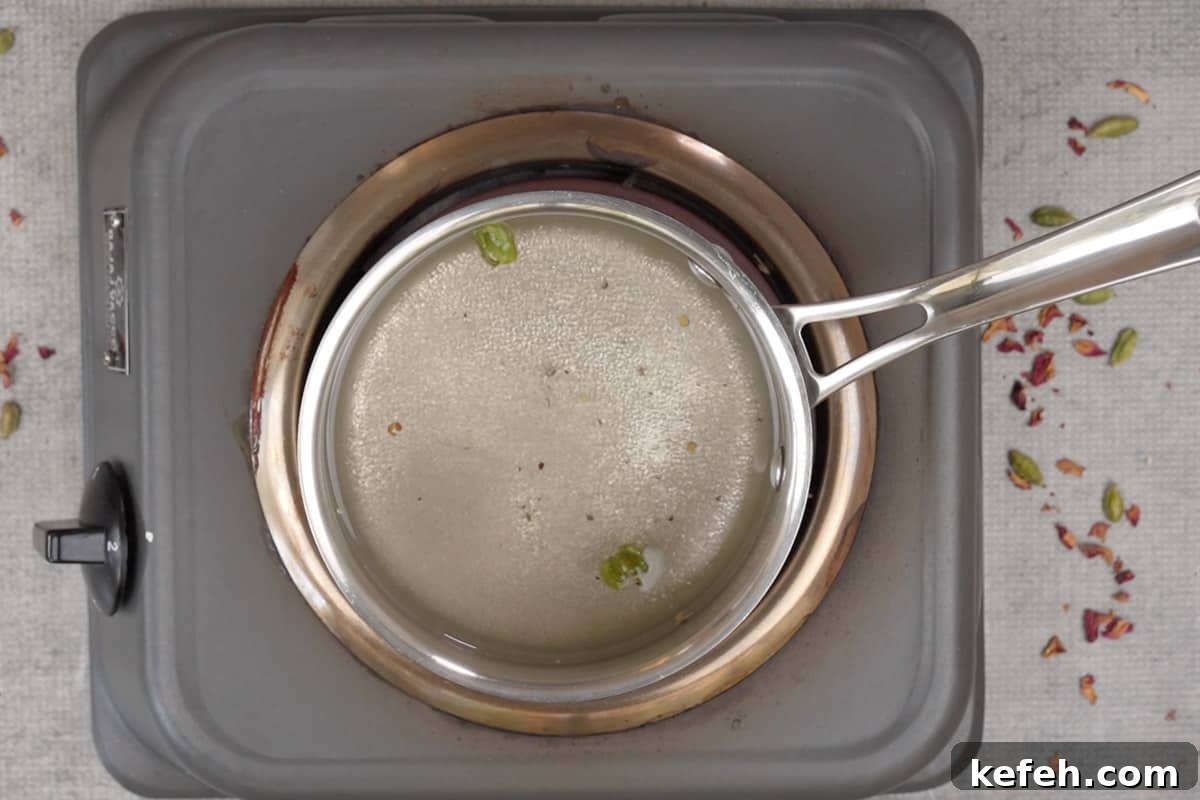 Water, sugar and cardamom added to a pan.