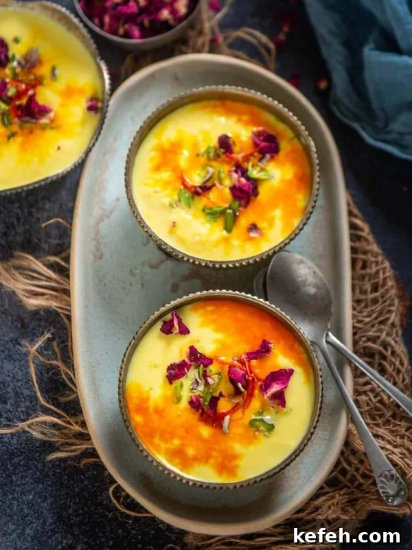 Two bowls of creamy yellow Rabdi, garnished with saffron, chopped pistachios, and dried rose petals.