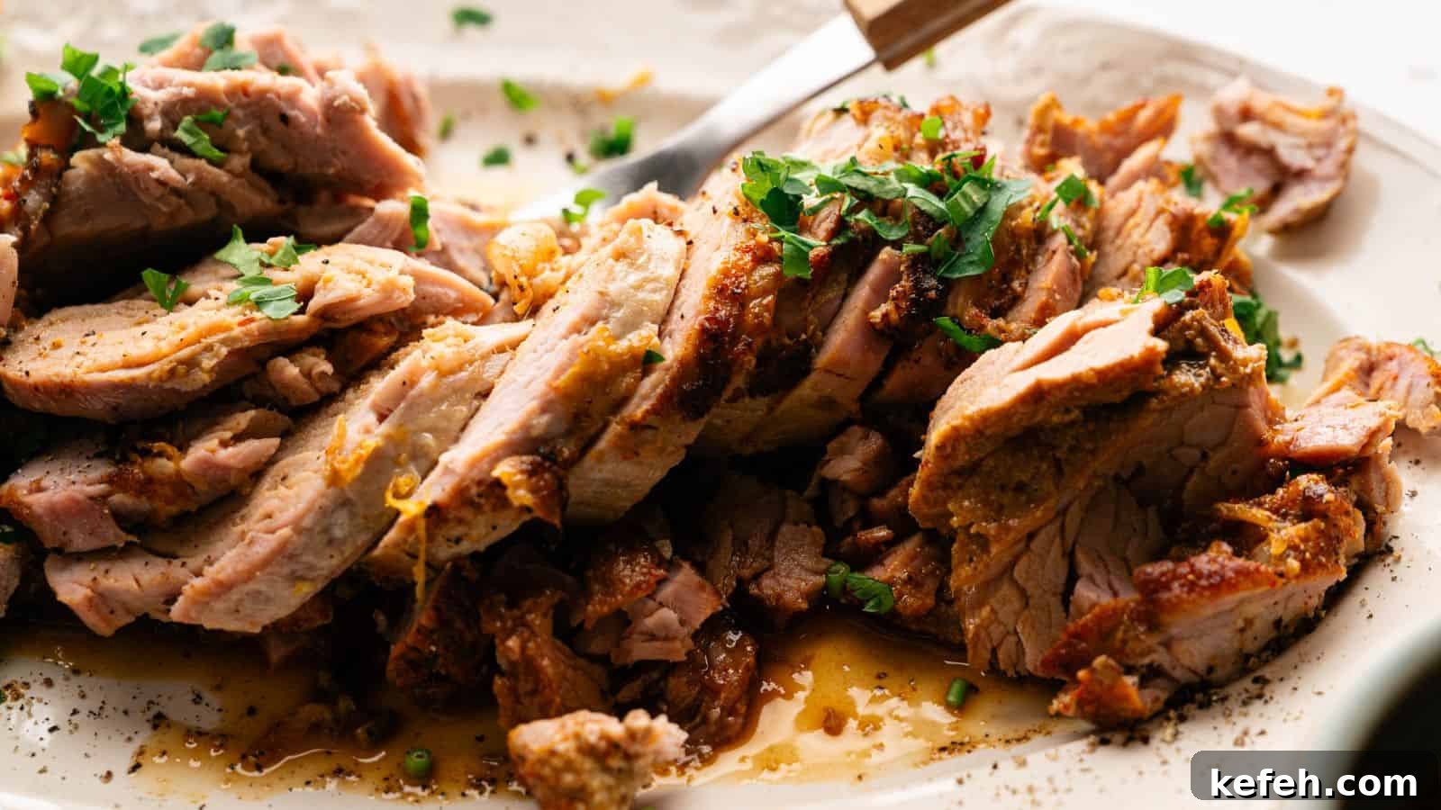 Sliced roasted pork garnished with chopped herbs is arranged on a plate, with visible juices and a serving fork nearby.