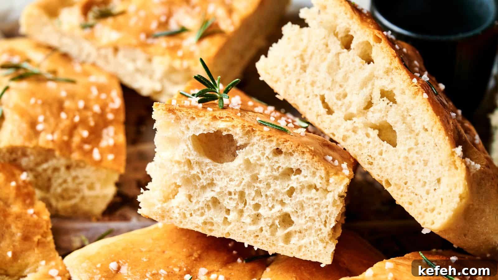 Close-up of sliced focaccia bread topped with coarse salt and rosemary, showing a light, airy crumb.