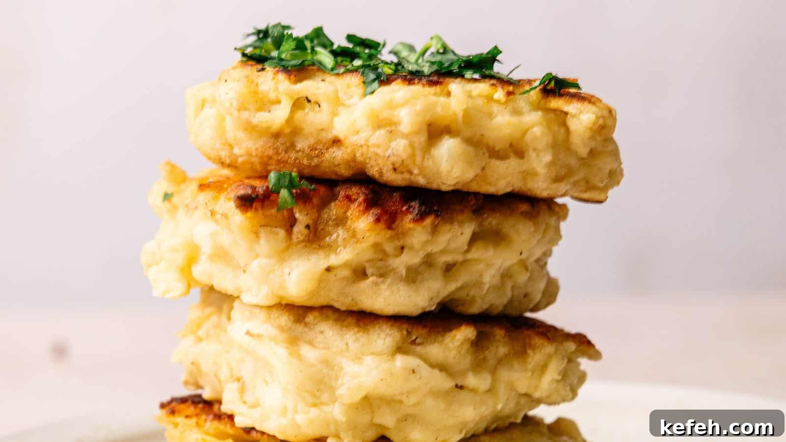Three golden-brown fritters stacked on a plate, garnished with chopped green herbs on top.