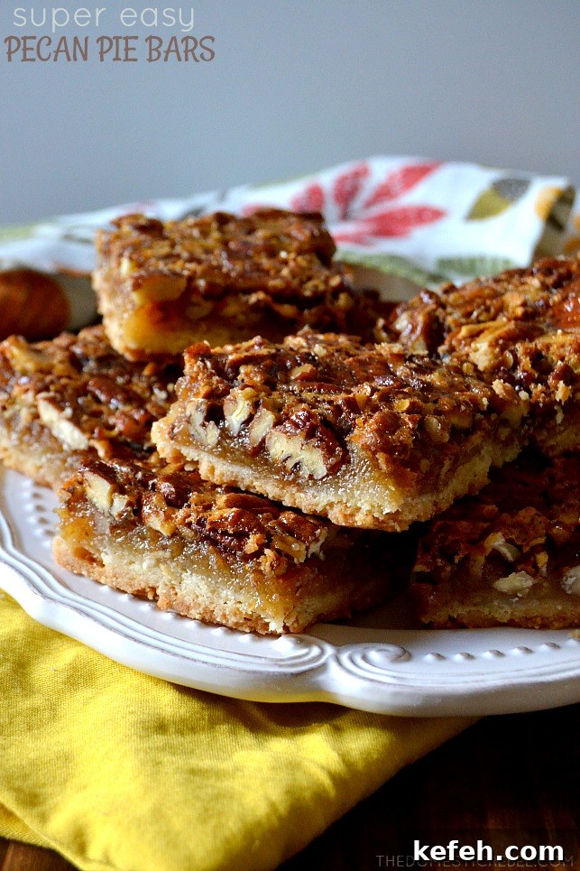 pecan pie bars arranged in a stacked formation on a white plate on top of a floral dish towel