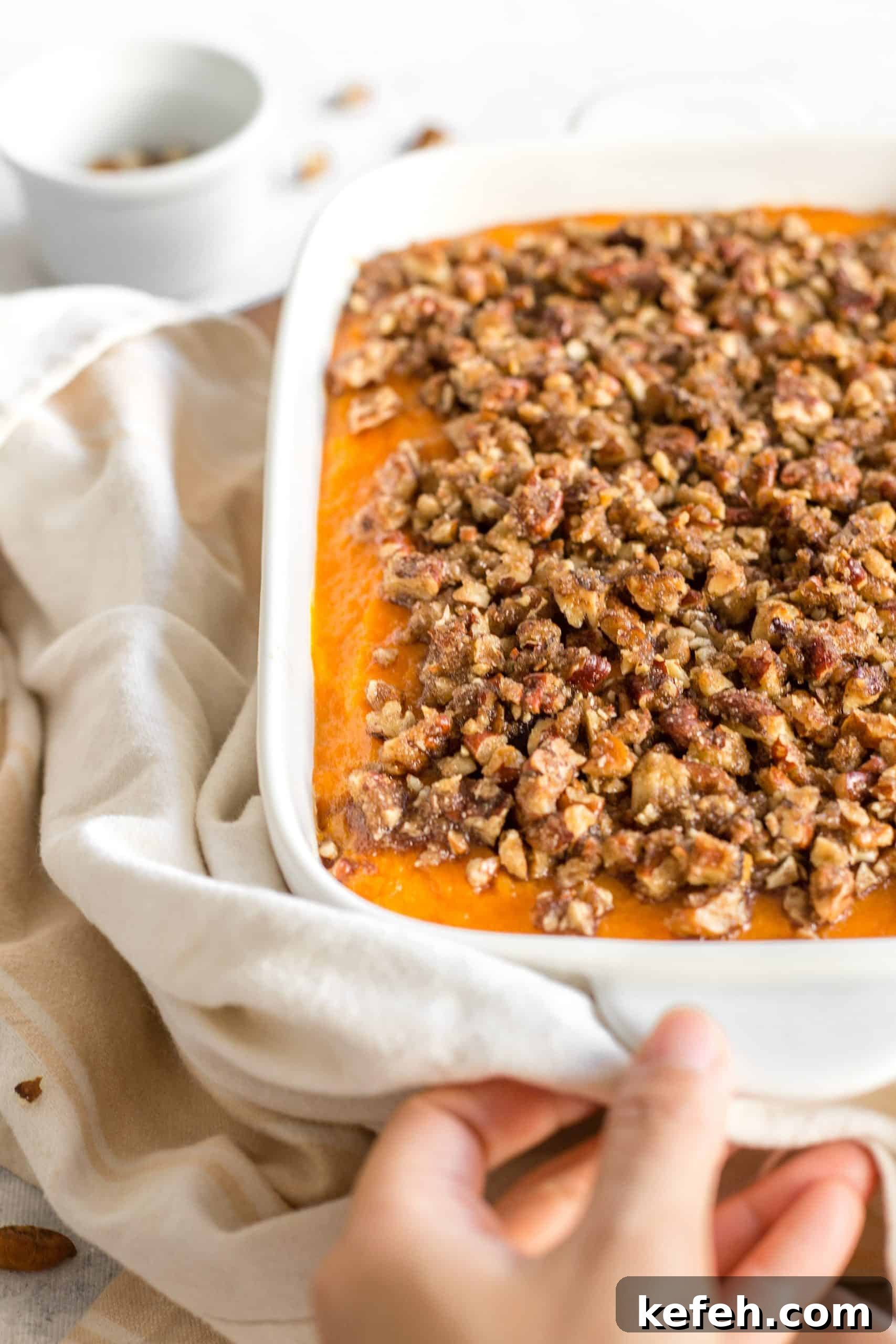 Gluten-Free Sweet Potato Casserole (Dairy-Free) Hand holding a casserole dish.