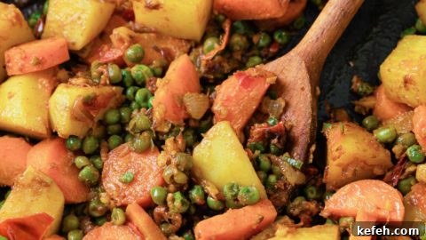 Mixed Vegetable Curry Recipe: Flavorful Indian Veggie Stew 12 Potatoes, carrots, and peas in a black pan with a wooden spoon