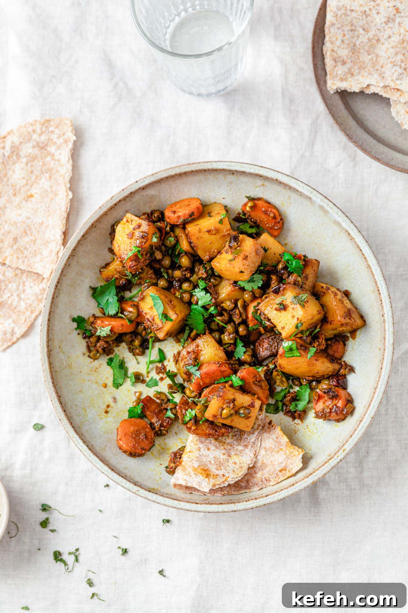 Mixed Vegetable Curry Recipe: Flavorful Indian Veggie Stew 7 Curried mixed vegetables in a bowl with bread and a glass of water on the side