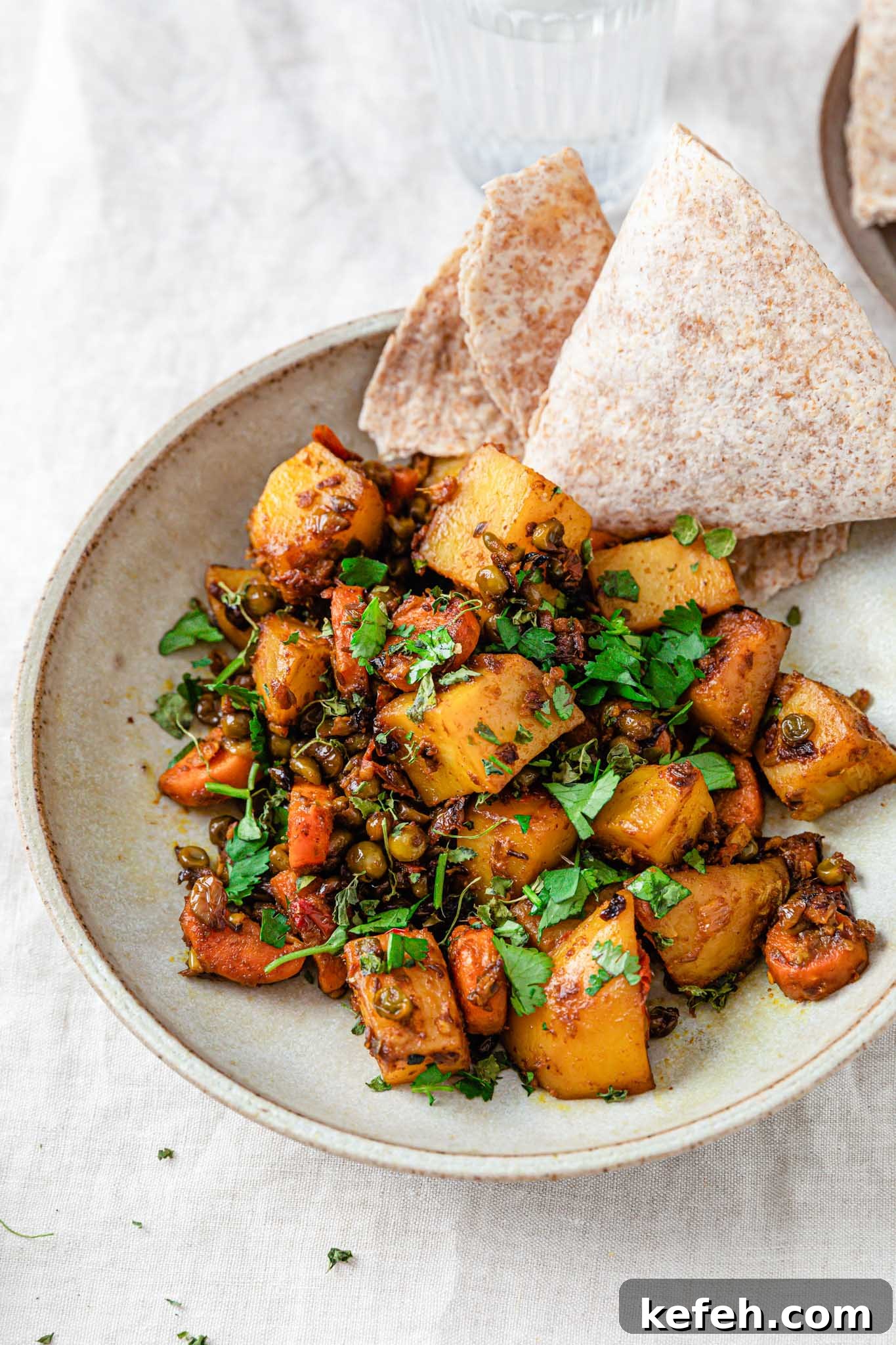 Mixed Vegetable Curry Recipe: Flavorful Indian Veggie Stew 9 Potatoes, carrots, and in a beige bowl with a piece of roti on the side.