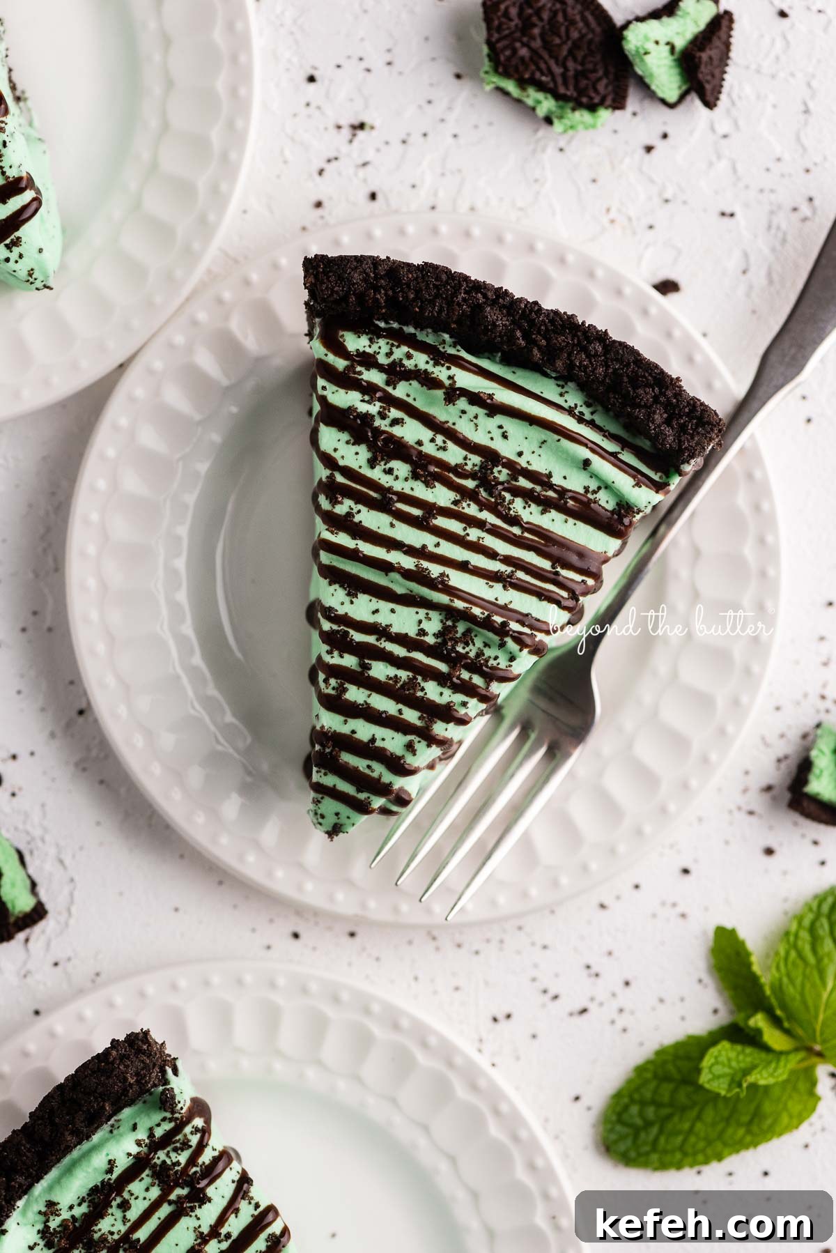Creamy No-Bake Mint Chocolate Pie Recipe 3 Dessert plates with slices of no bake mint chocolate pie with chocolate syrup drizzled over the top | © Beyond the Butter®