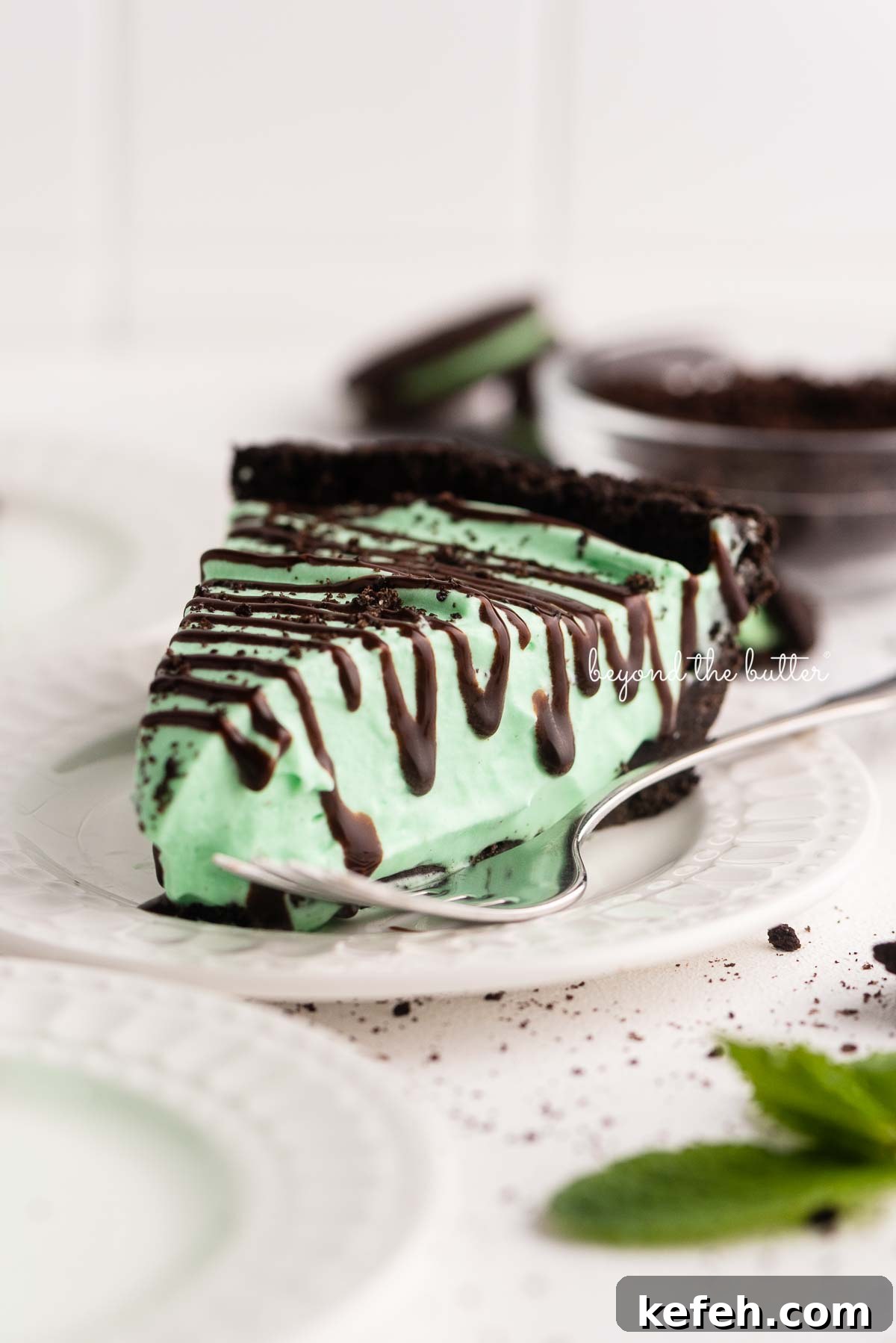 Creamy No-Bake Mint Chocolate Pie Recipe 4 Dessert plates with slices of no bake mint chocolate pie with chocolate syrup drizzled over the top | © Beyond the Butter®