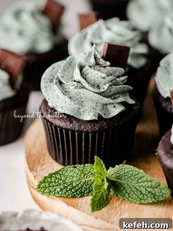 Creamy No-Bake Mint Chocolate Pie Recipe 8 Mint chocolate cupcakes topped with mint chocolate chip frosting and an Andes mint on a wood circular tray with mint leaves as decoration.