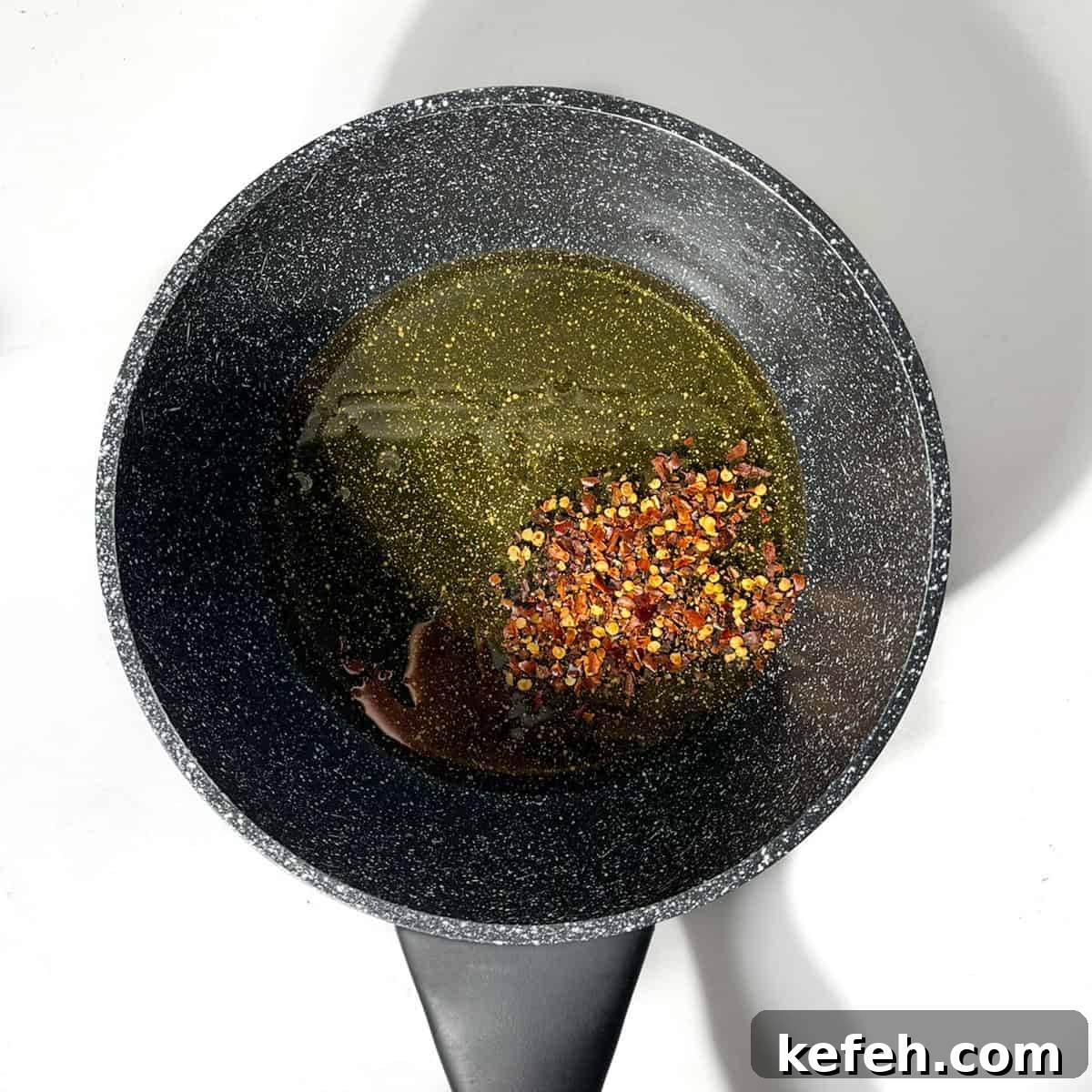 Honey and chilli flakes in a black saucepan.