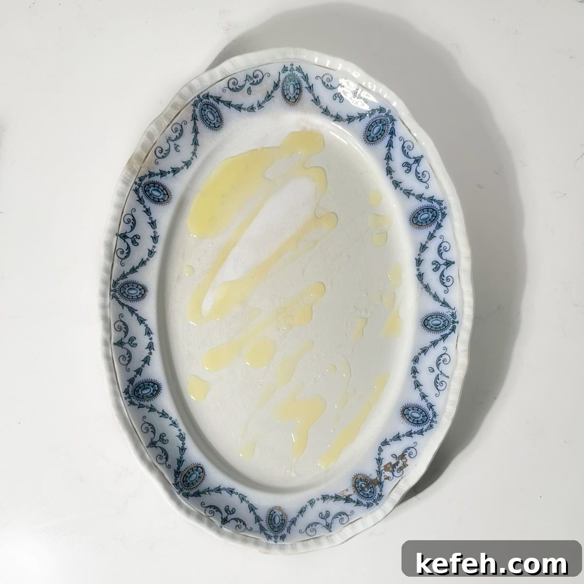 A white oval dish with olive oil drizzled on the surface.