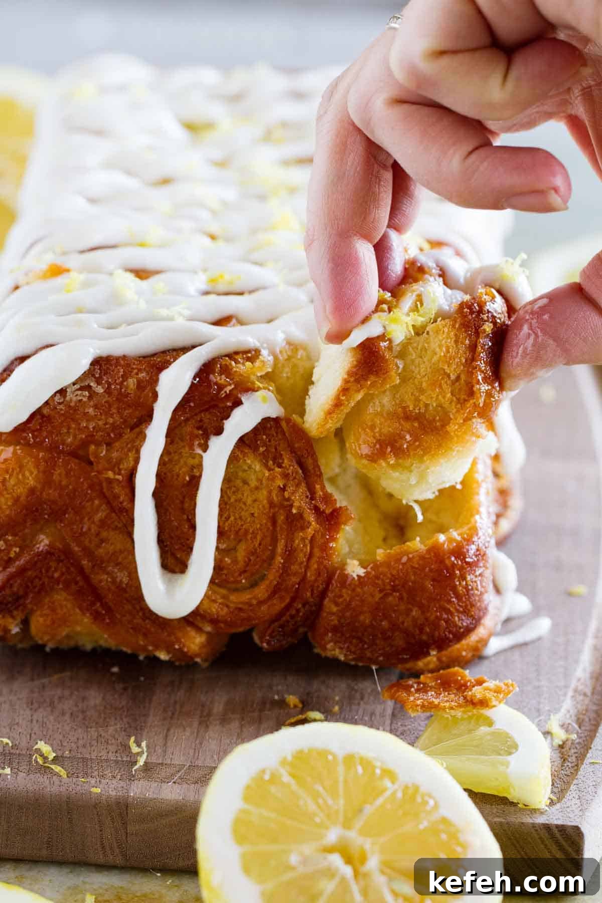 Fingers pulling a piece of lemon roll pull apart bread from the loaf.