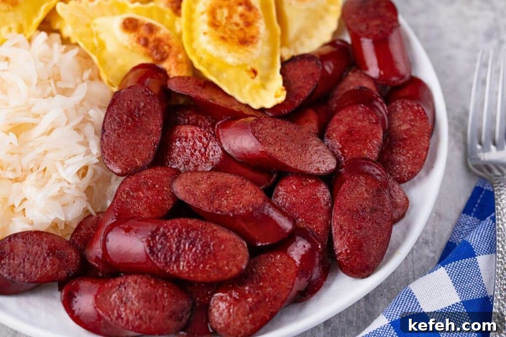 Crispy Juicy Air Fryer Kielbasa Recipe That Melts in Your Mouth 10 air fryer kielbasa slices on a plate with sauerkraut and pierogies as a side
