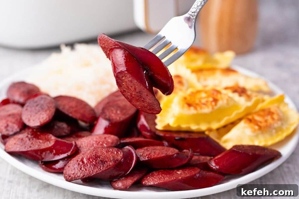 Crispy Juicy Air Fryer Kielbasa Recipe That Melts in Your Mouth 3 holding up a fork with two kielbasa slices over a plate of more kielbasa pierogies and sauerkraut