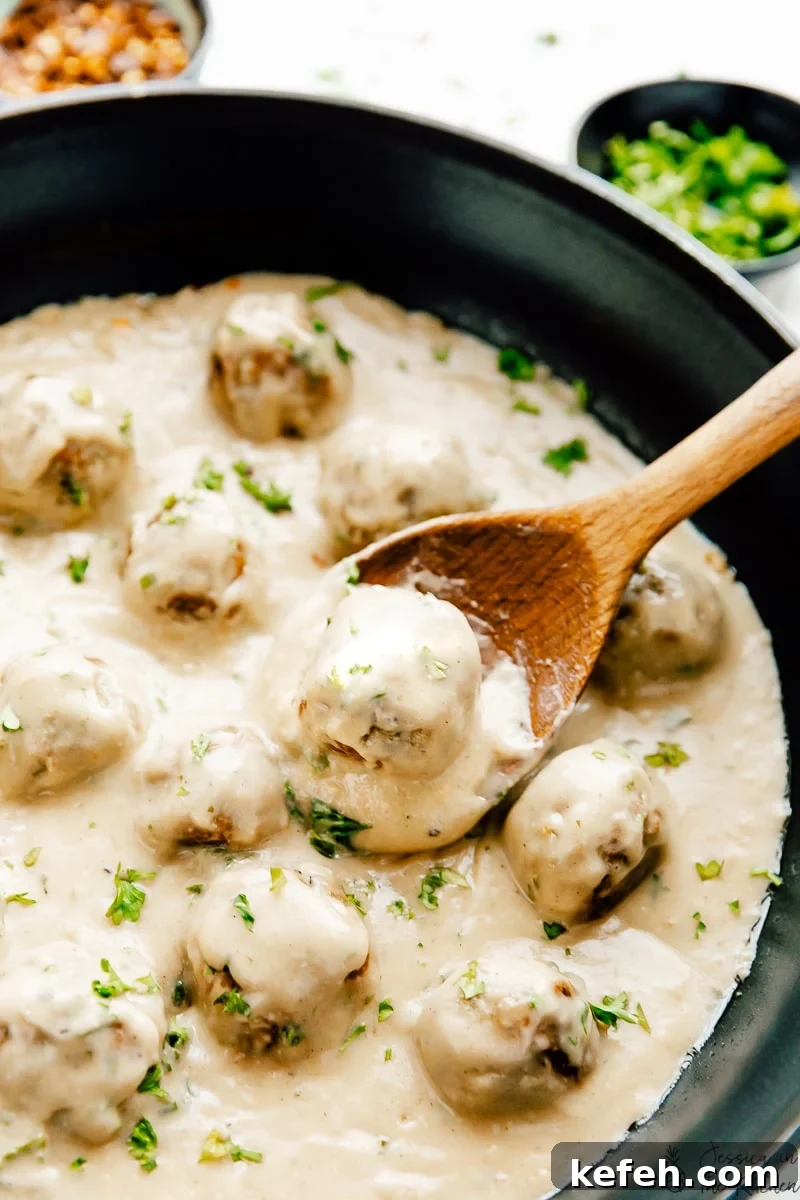 Vegan Swedish meatballs in skillet with wooden spoon