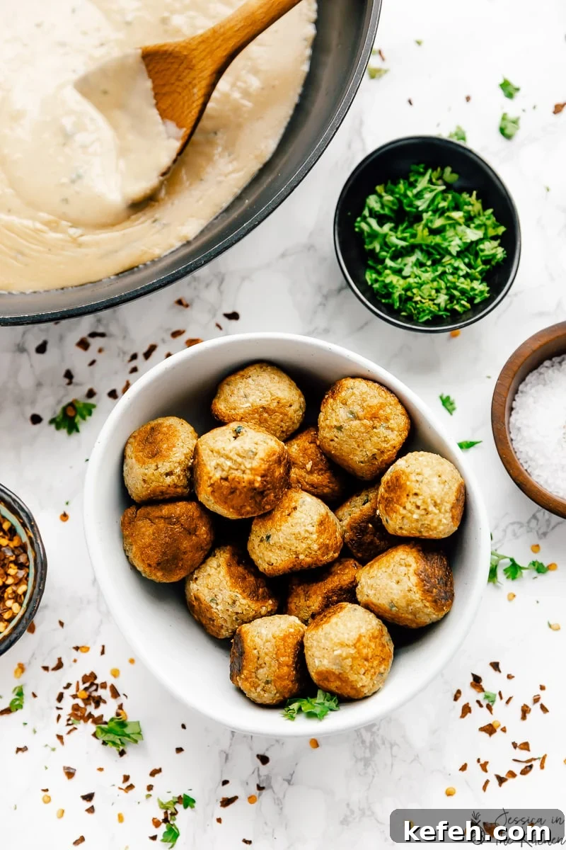 Vegan meatballs in a bowl with sauce and other ingredients around it