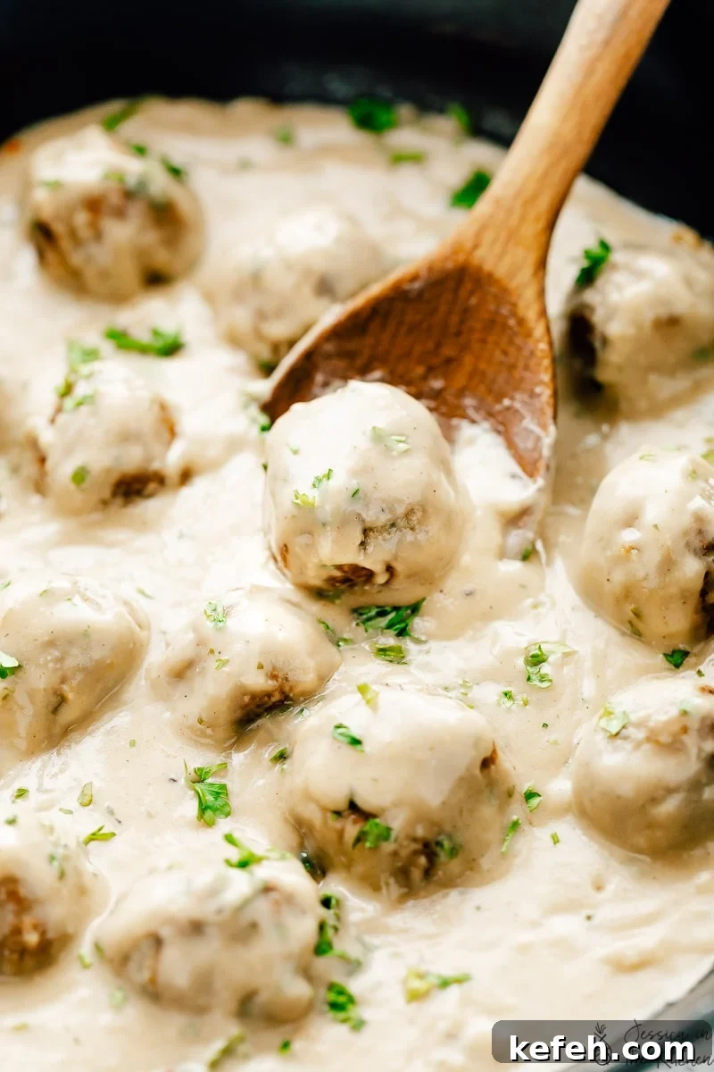 Vegan Swedish meatballs in skillet with wooden spoon, garnished with parsley