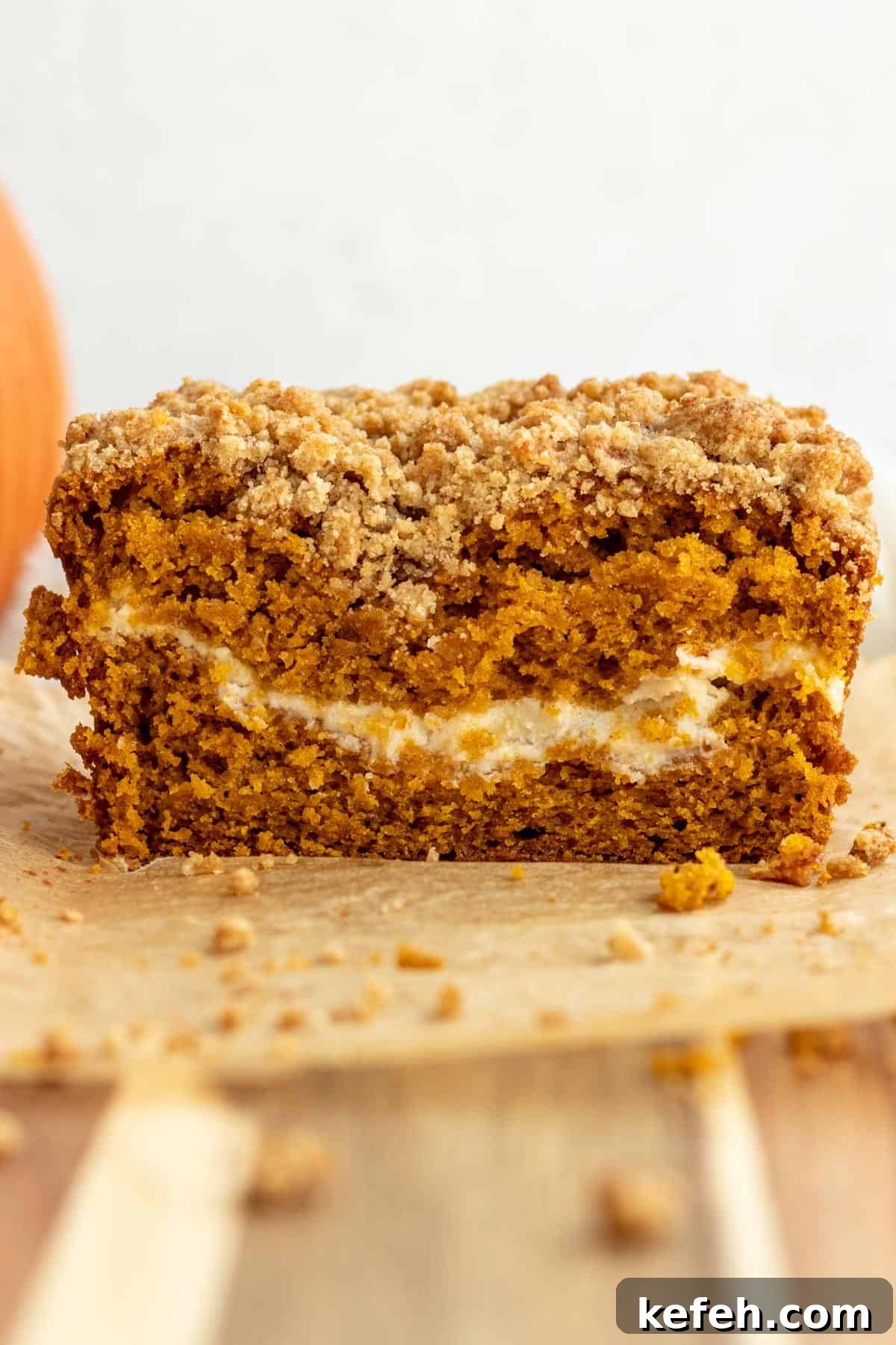 close up of a loaf of pumpkin cream cheese bread cut into showing layer of cream cheese in the bread