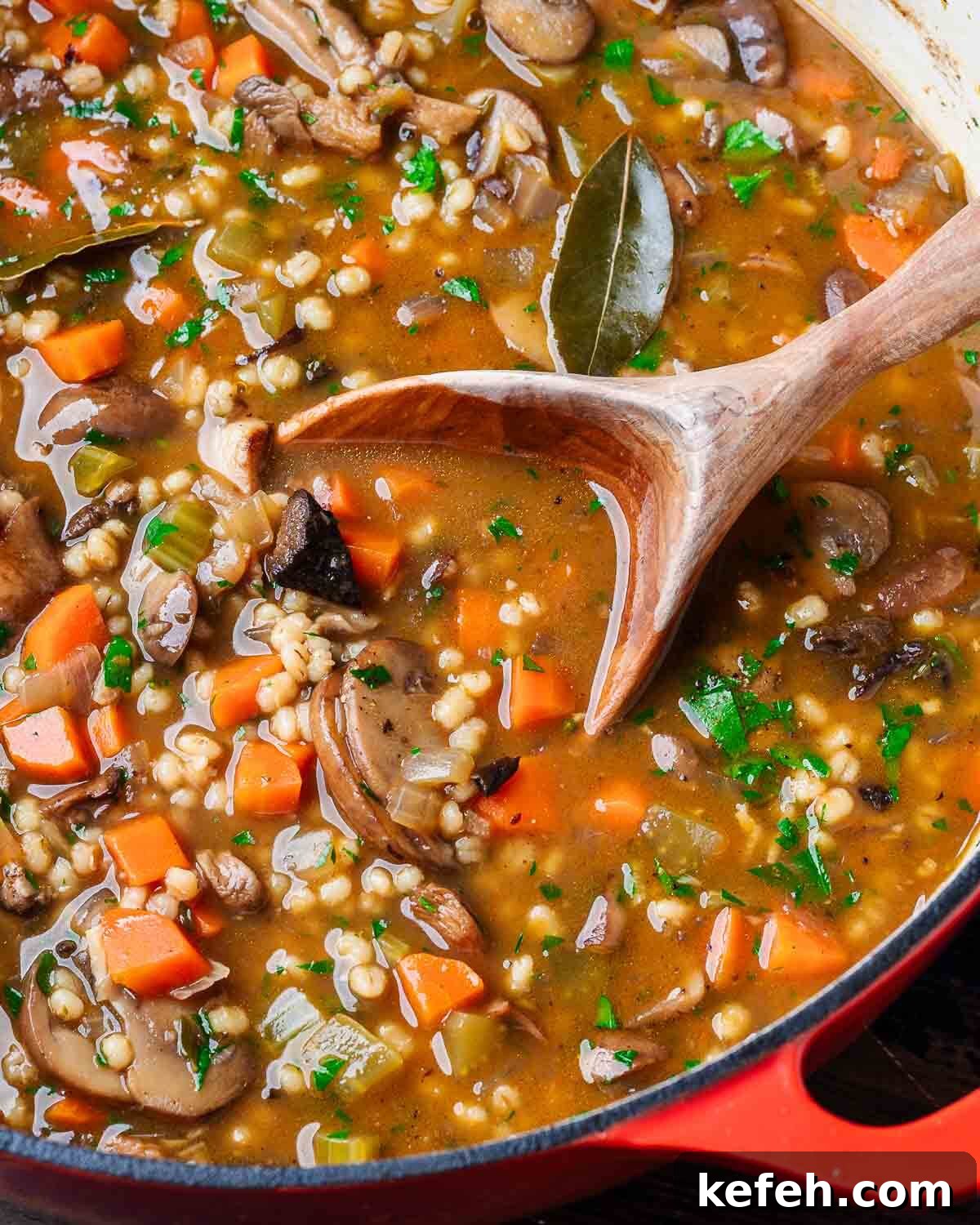 Large pot of mushroom barley soup with wooden ladle.