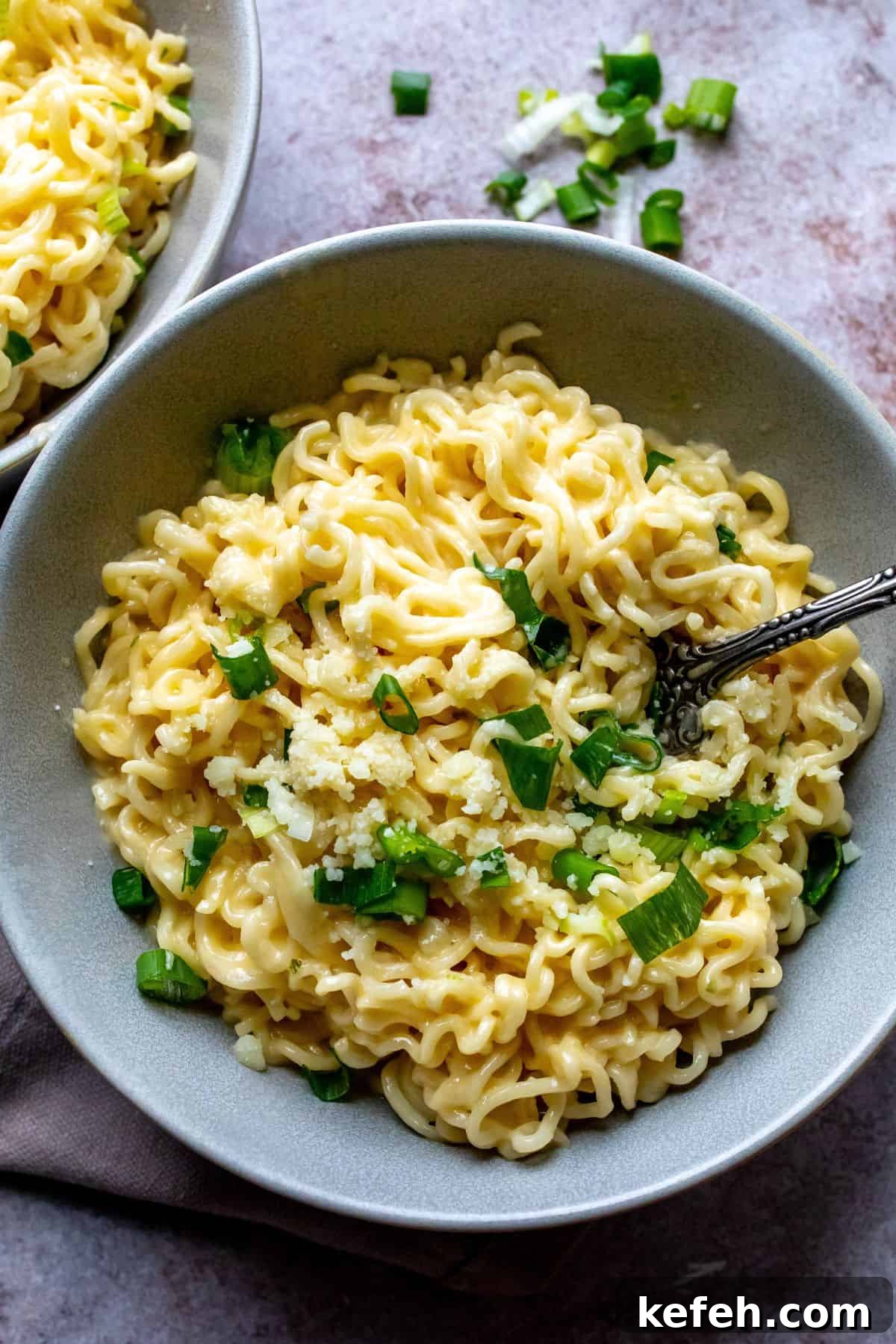 10-Minute Creamy Cheesy Ramen 2 Grey ceramic bowl with green onions and cheesy ramen.
