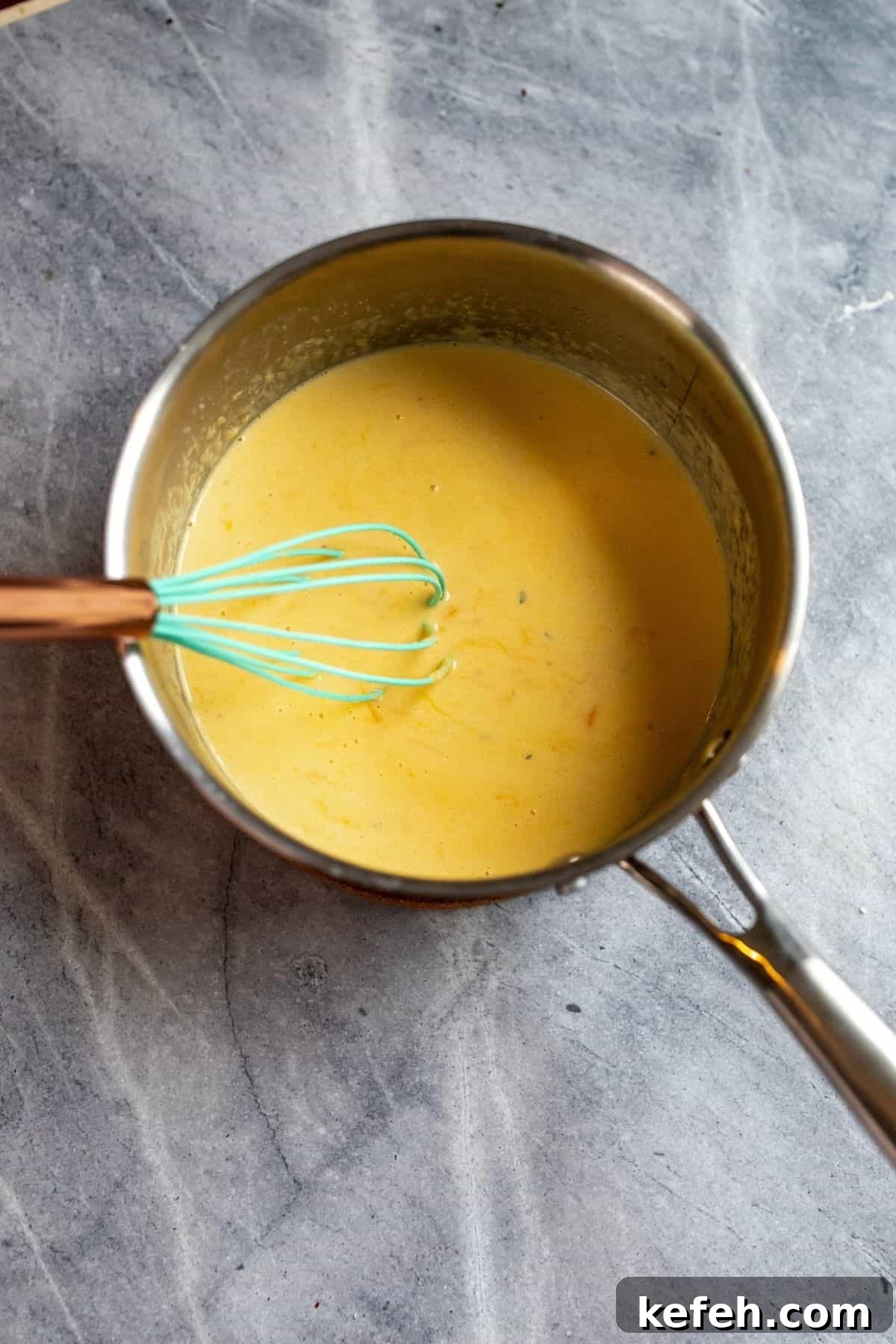 10-Minute Creamy Cheesy Ramen 4 Stainless Steel pot with melted cheese sauce in it and whisk.