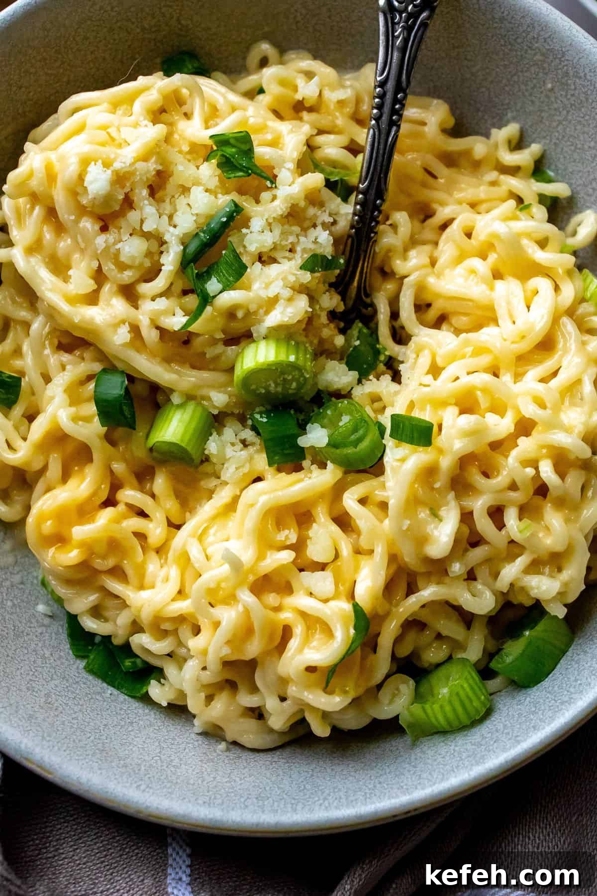 10-Minute Creamy Cheesy Ramen 5 Grey bowl with cheesy ramen in it and green onions