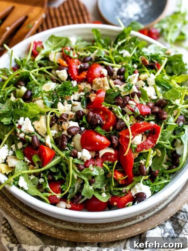 10-Minute Creamy Cheesy Ramen 7 Mediterranean Black Bean Salad in a ceramic white bowl with salad serving utensils.