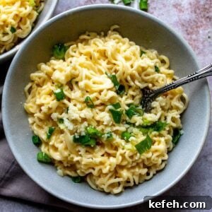 10-Minute Creamy Cheesy Ramen 10 Grey ceramic bowl with green onions and cheesy ramen.