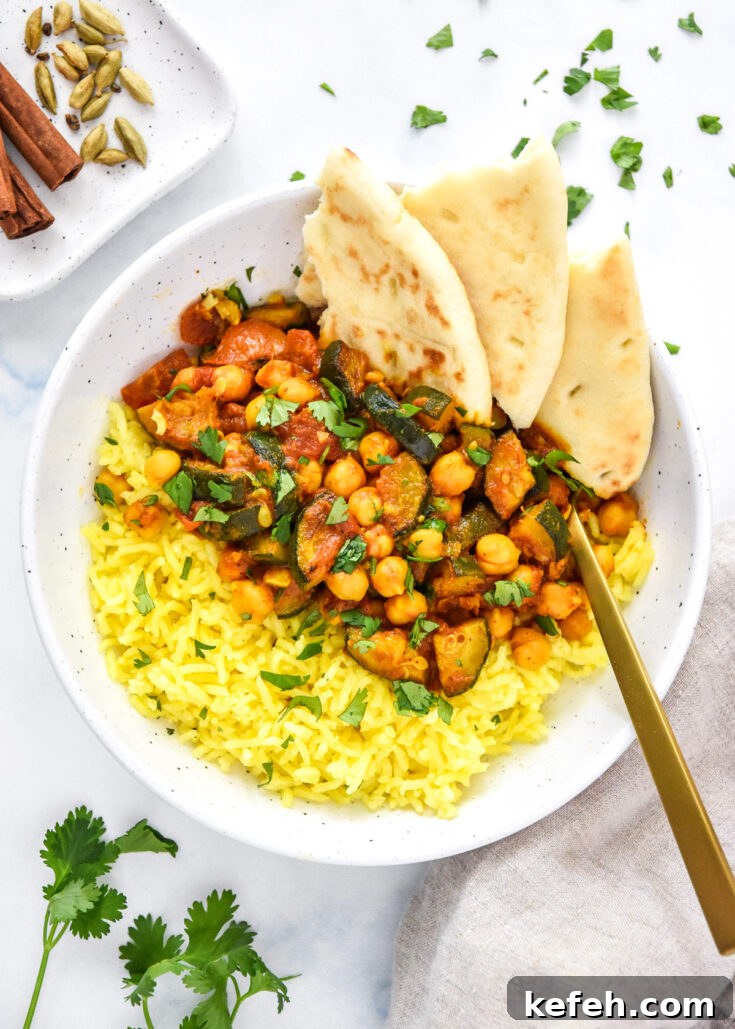zucchini chickpea curry meal prep in a bowl with turmeric rice and naan bread.