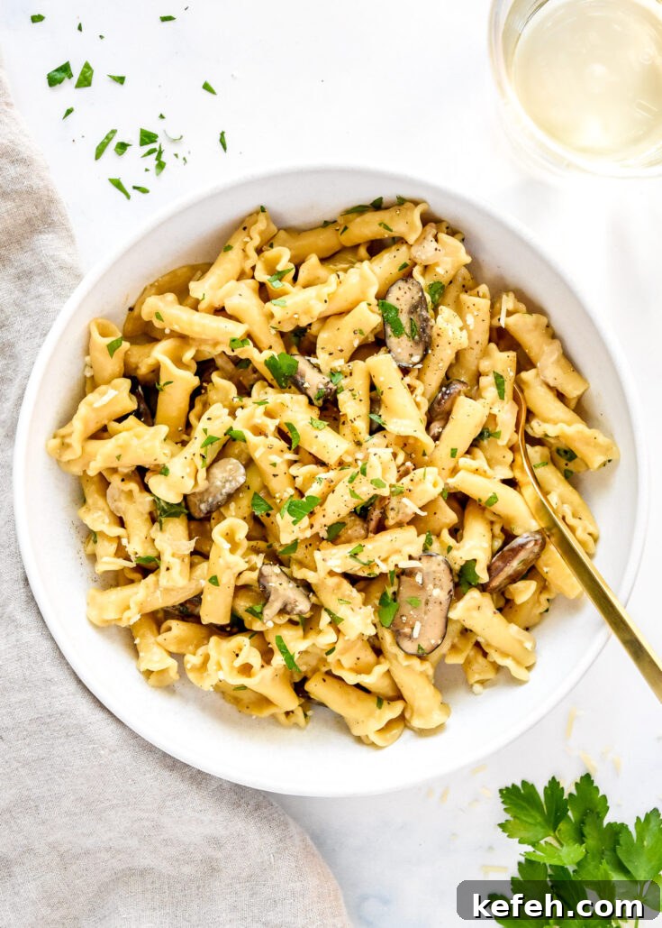 one pot creamy mushroom pasta in a white bowl with gold fork.
