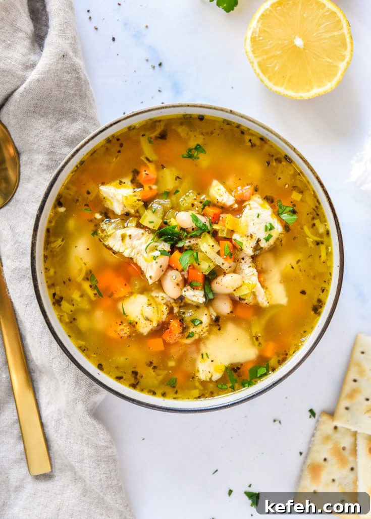 15 Cozy Fall Recipes to Try This Season 7 white bean lemon chicken soup in a bowl with veggies and broth, crackers and lemon on the side.