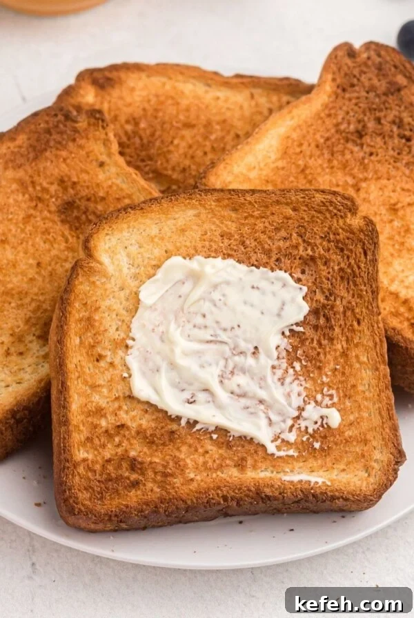 Golden toast with one being buttered. Served on a white plate with blueberries and butter.