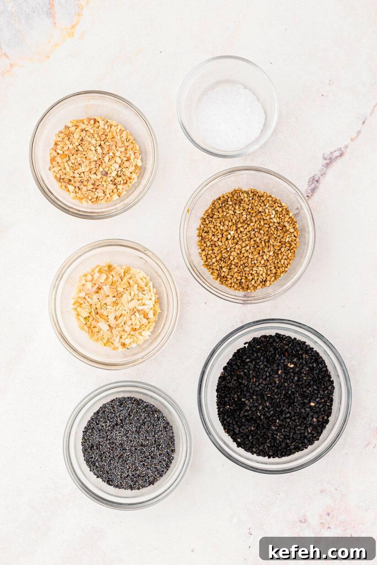 Seeds and seasonings measured out in small glass bowls.