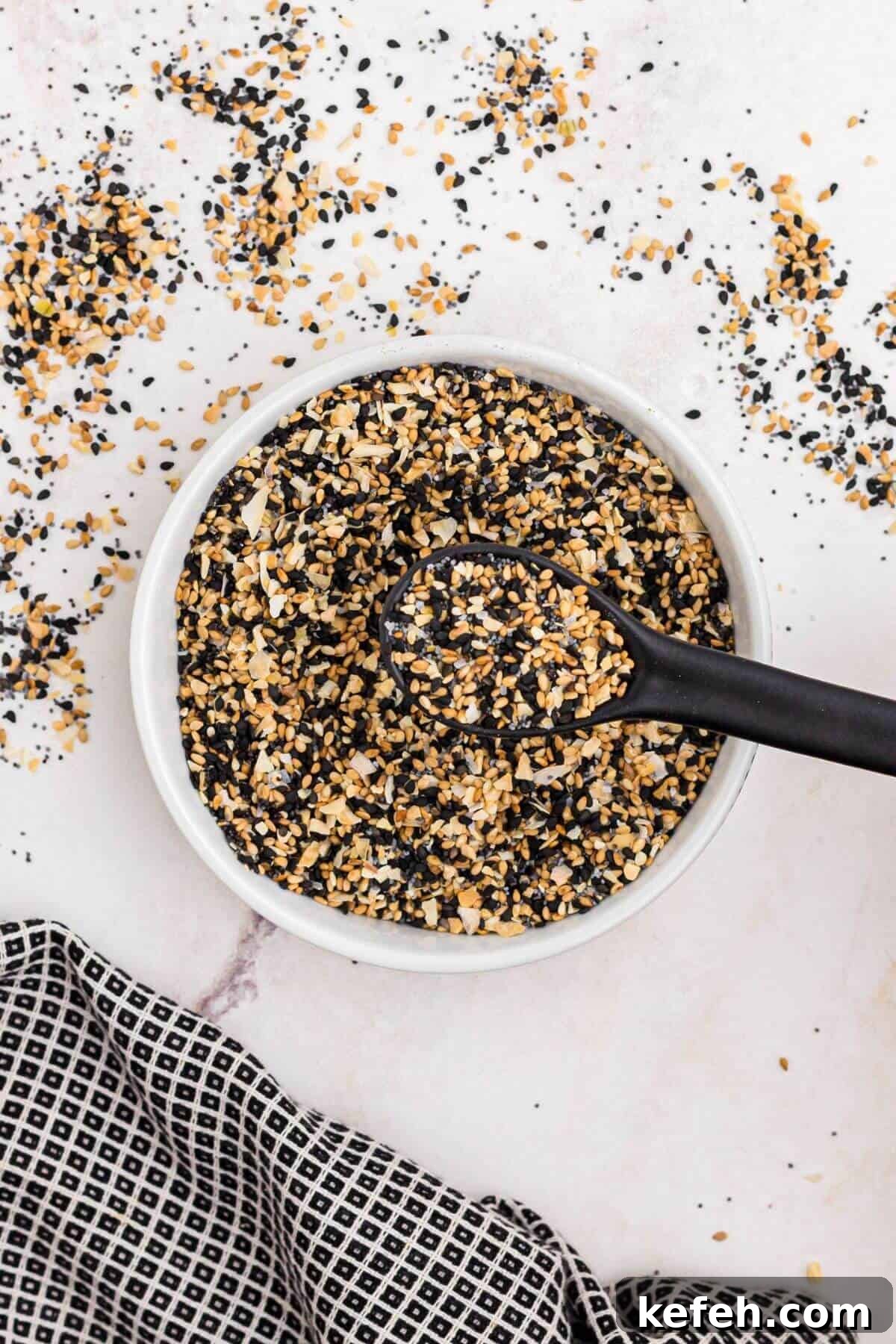 Seeds and seasonings in a small white bowl mixed together with a black spoon.