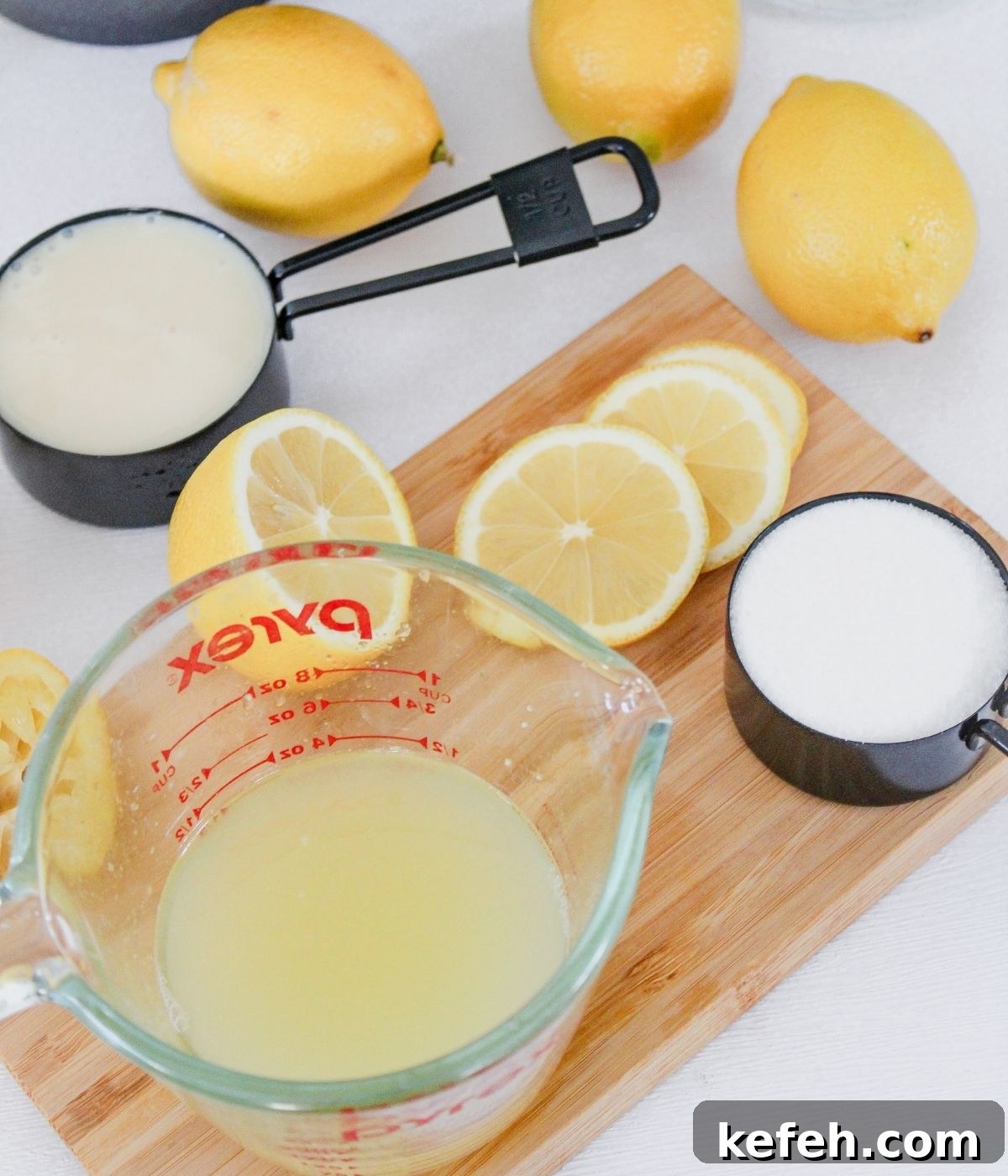 Table with lemon juice, sugar, sweetened condensed milk, and lemons.