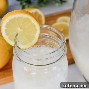 Mason jar glass of creamy lemonade drink with a lemon slice on the side.