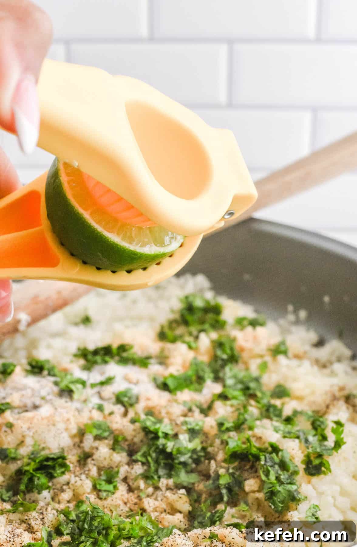 Cilantro Lime Cauliflower Rice Recipe for Flavorful Low-Carb Sides 7 Squeezing lime juice into a pan of cilantro cauliflower lime rice and herbs using a handheld citrus juicer.
