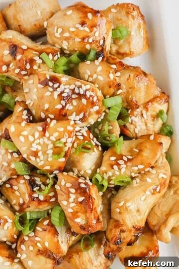 Pieces of air fried teriyaki chicken on a white plate.