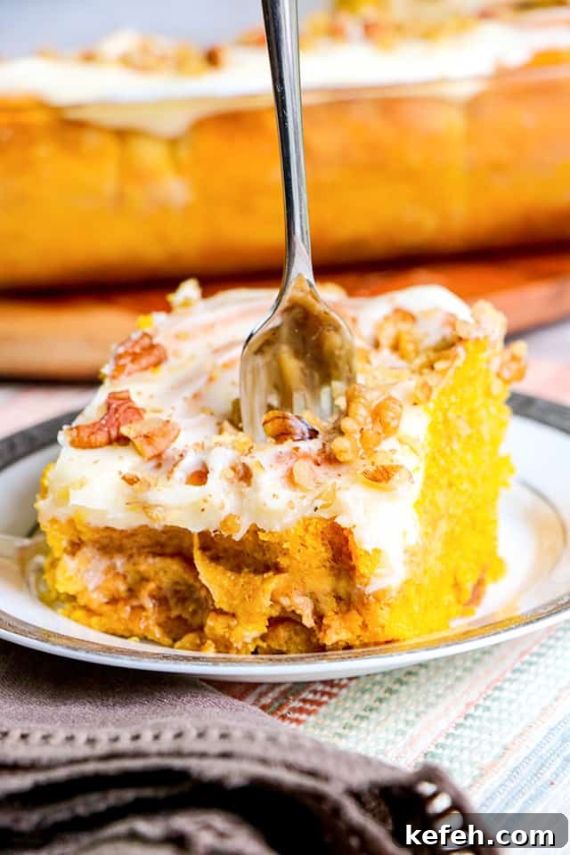 pumpkin cinnamon roll on a silver trimmed plate with a dish of cinnamon rolls behind it