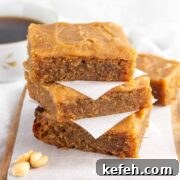 A stack of keto iced peanut butter bars with a cup of coffee in the background.