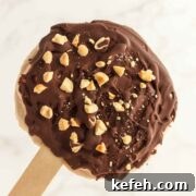 Creamy sweet frozen vanilla peanut butter yogurt with a chocolate coating sprinkled with chopped nuts.