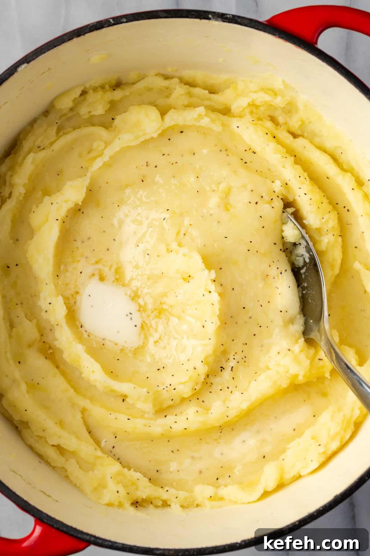 A dutch oven filled with gluten free mashed potatoes topped with melting butter.