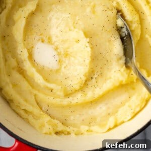 Gluten free mashed potatoes in a large pot topped with melted butter.